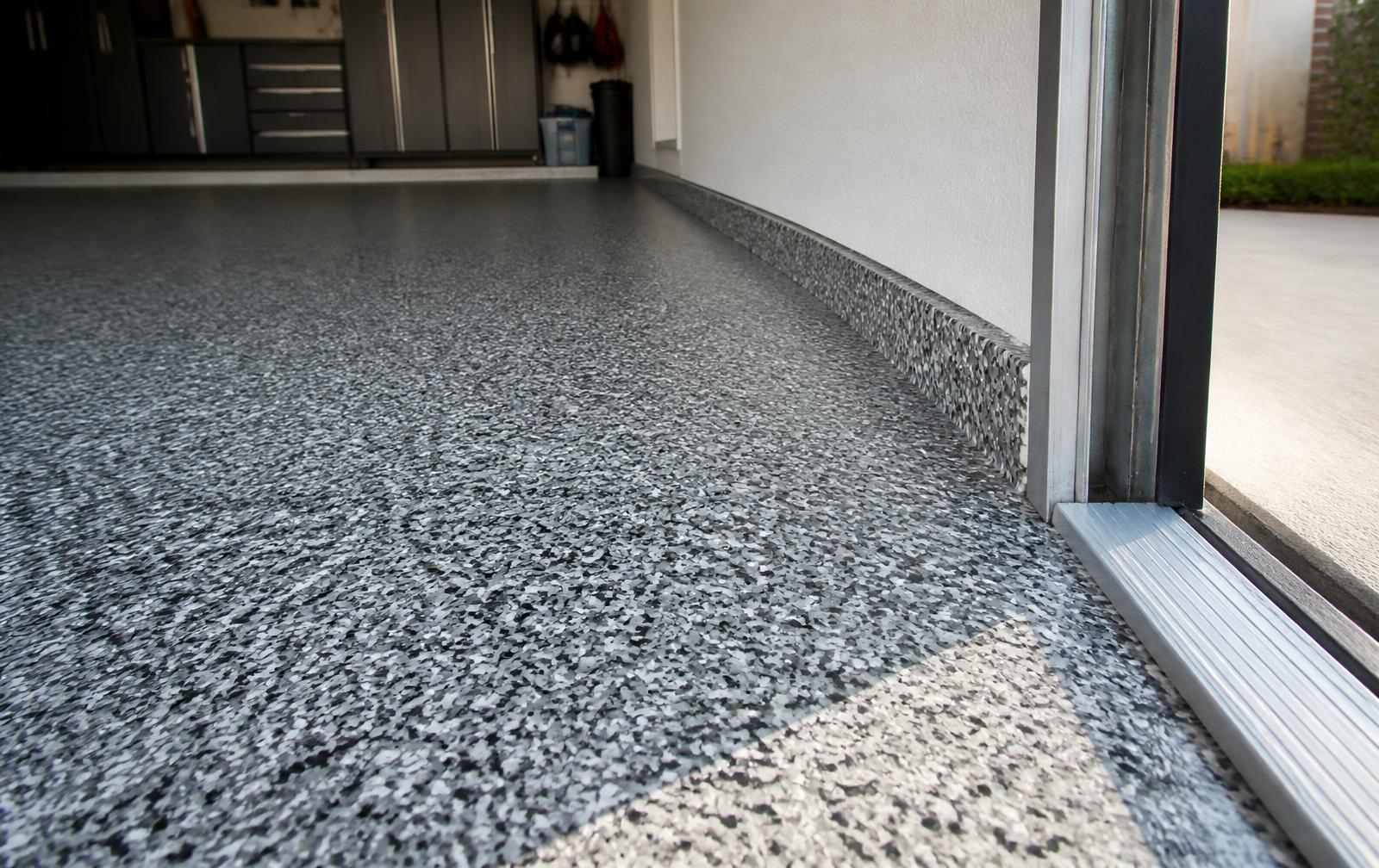 Close view of a gray and black decorative flake epoxy garage floor with clean edge detail