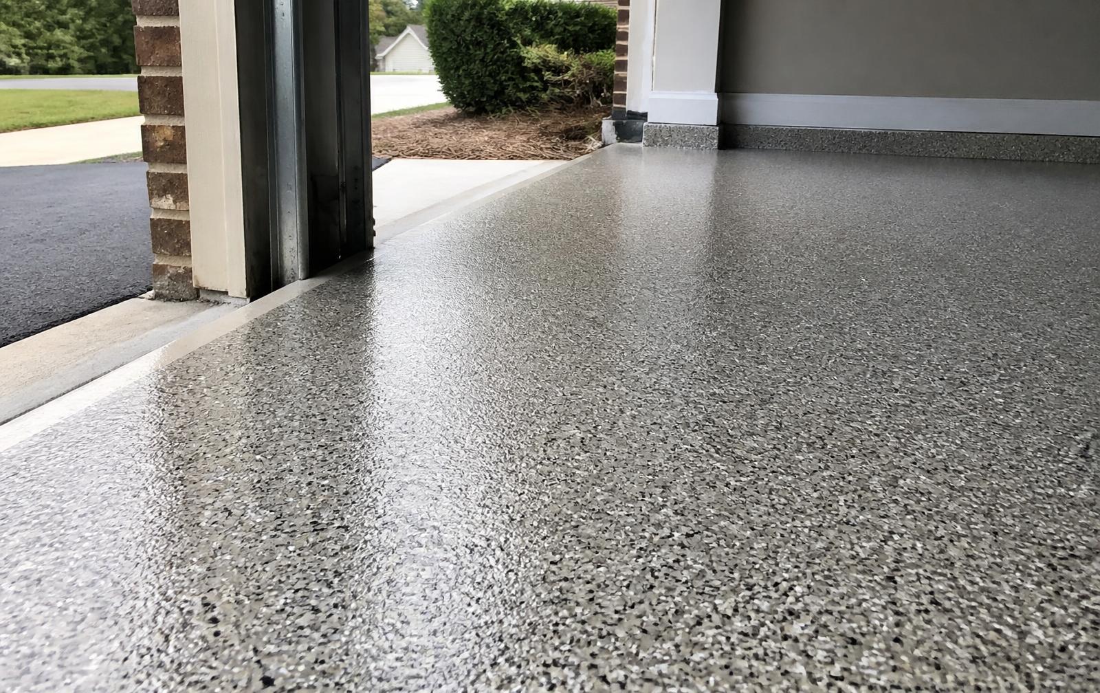 Finished gray and tan flake epoxy garage floor with a clean threshold edge at a Forestbrook home