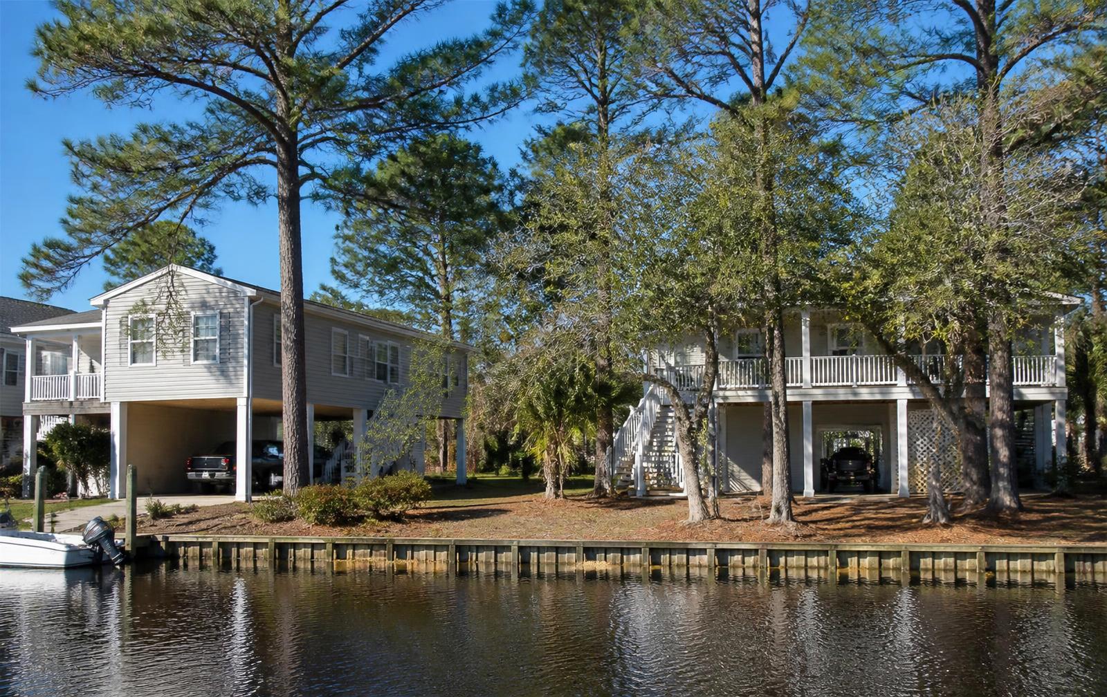 Waterfront homes with carports beside a calm waterway in Little River, SC