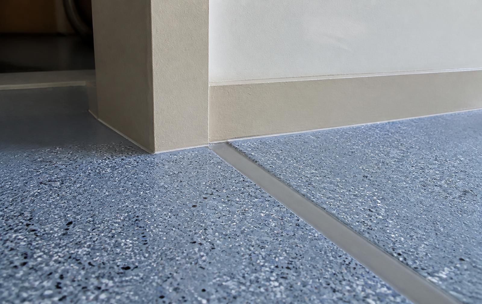 Repaired control joint and clean wall edge on a blue-gray flake epoxy garage floor in Murrells Inlet