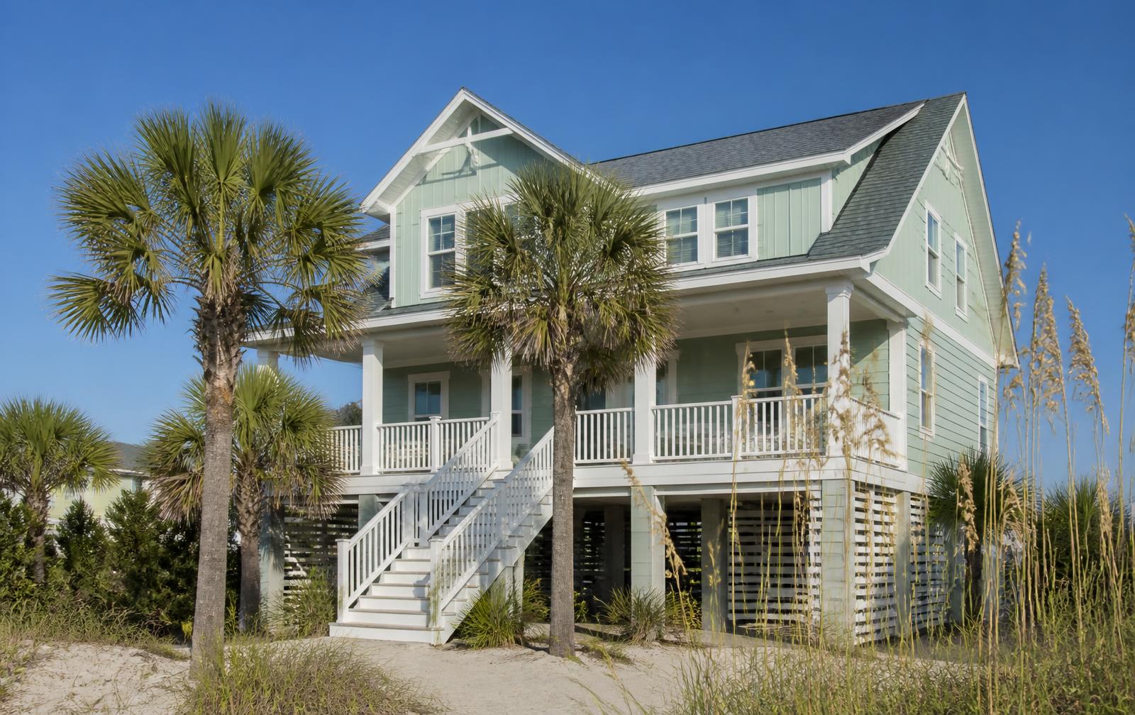 Raised pastel beach cottage with palmettos and sea oats in Surfside Beach, SC